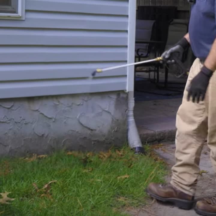 Pest control worker checking the exterior foundation of a home